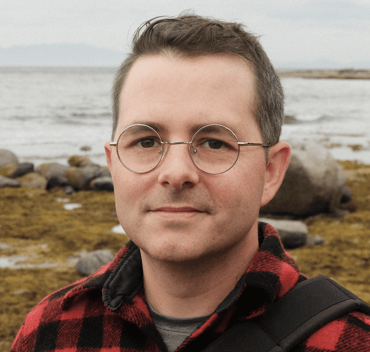 Person in glasses by rocky seaside.