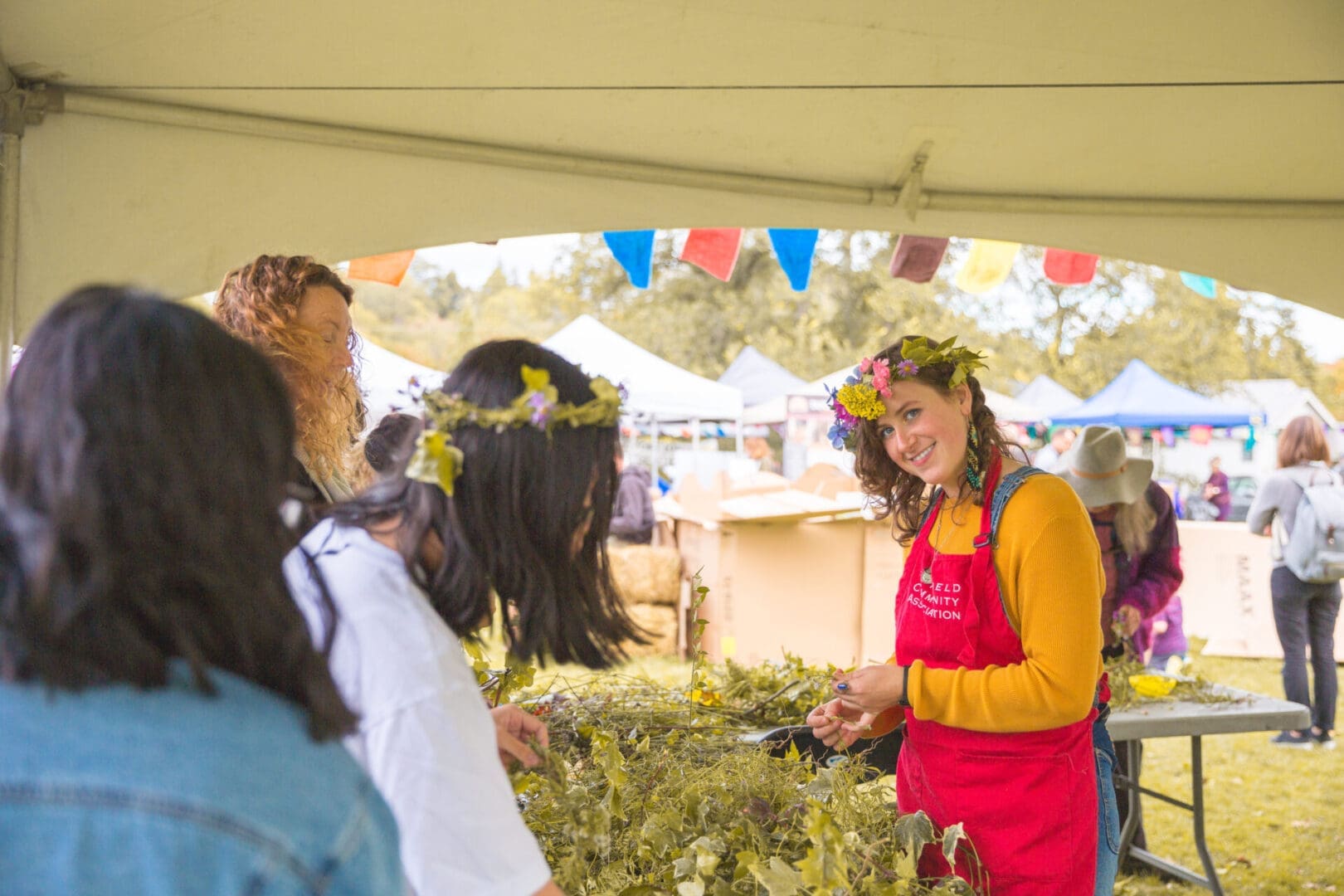 People crafting wreaths at outdoor festival booth.